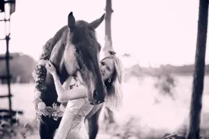 Junge Frau mit ihrem Pferd und Blumenkranz im Sommer beim Fotoshooting