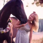 Frau spielt beim Blumenkranzshooting mit Ihrem Pferd